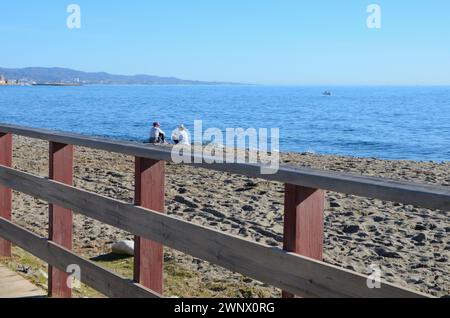 Marbella, Espagne - 10 décembre 2023 : deux femmes assises sur la plage de sable par une journée ensoleillée de décembre à Marbella, Andalousie, Espagne. Banque D'Images