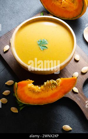 Soupe de carottes à la citrouille maison avec persil dans un bol et citrouilles fraîches sur fond rustique Banque D'Images