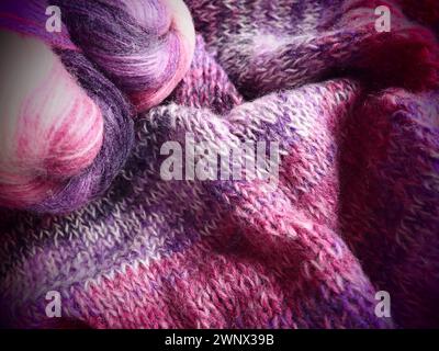 Tricoter une écharpe ou un pull à partir de fil blanc, rose et violet. Boules de laine et de fils acryliques. Tricoter comme passe-temps. Accessoires, aiguilles à tricoter Banque D'Images
