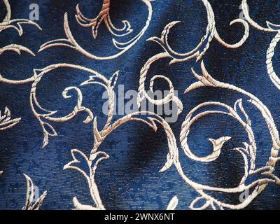 tissu bleu soie avec boucles dorées. Textiles pour tissus d'ameublement, rideaux et vêtements de fête. Le tissu est doucement plié en vagues. Banque D'Images