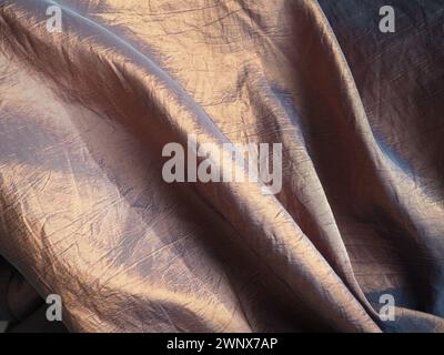 Beau tissu - taffetas, délicatement plié en vagues. Matière froissée qui ressemble à de la soie ou du brocart. Débordement et dégradé de couleurs à différents Banque D'Images