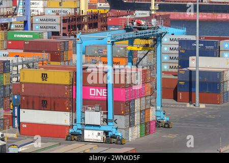 Puerto Quetzal, Guatemala - 19 janvier 2024 : grue fonctionnant au-dessus d'une pile de conteneurs empilés dans le port de la ville Banque D'Images