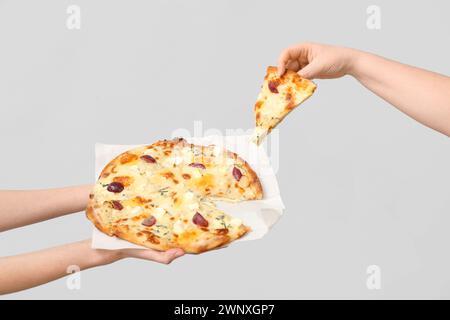 Mains féminines tenant une pizza savoureuse sur fond blanc Banque D'Images