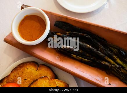 Les oignons calcottes sont servis sur une assiette avec une sauce Romesco - plat traditionnel catalan Banque D'Images