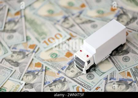 Camion de livraison sur des billets de cent dollars. Arrière-plan du concept de déménagement ou de camionnage en gros plan Banque D'Images