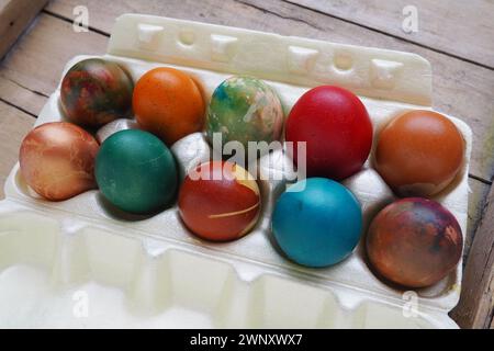 Les oeufs colorés de Pâques se rapprochent dans un emballage en plastique. Dix œufs de vacances colorés sont empilés les uns à côté des autres. Oeufs de poule durs avec floral et Banque D'Images