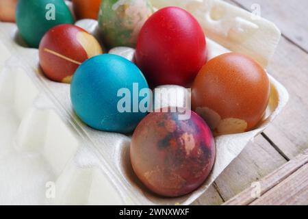 Les oeufs colorés de Pâques se rapprochent dans un emballage en plastique. Dix œufs de vacances colorés sont empilés les uns à côté des autres. Oeufs de poule durs avec floral et Banque D'Images