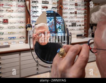 Pensionné essayant de nouvelles montures de lunettes dans un magasin d'optique, 2024, New York City, USA Banque D'Images