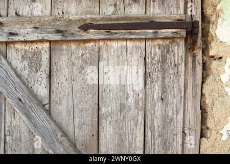 Vieille porte en bois verrouillée d'une grange rurale. Texture d'une planche de bois et agrafes de fer rouillées. Porte fermée d'un bâtiment ancien. Abandonné, oublié Banque D'Images