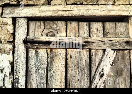 Vieille porte en bois verrouillée d'une grange rurale. Texture d'une planche de bois et agrafes de fer rouillées. Porte fermée d'un bâtiment ancien. Abandonné, oublié Banque D'Images