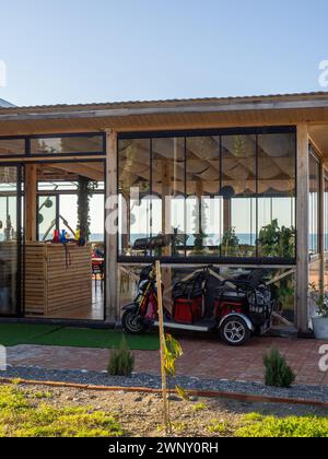 Petite voiture électronique pour le parc. Voiturette de golf. Véhicule stationné. Extérieur d'un restaurant sur la plage. Resort Banque D'Images