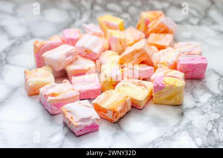 Guimauves maison colorées rose, orange et jaune faites de blancs d'œufs et de sucre sur un fond de marbre Banque D'Images