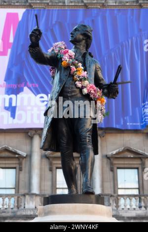 La statue du peintre Joshua Reynolds devant la Royal Academy of Arts de Londres, décorée d'une guirlande de fleurs pour l'exposition d'été. Banque D'Images