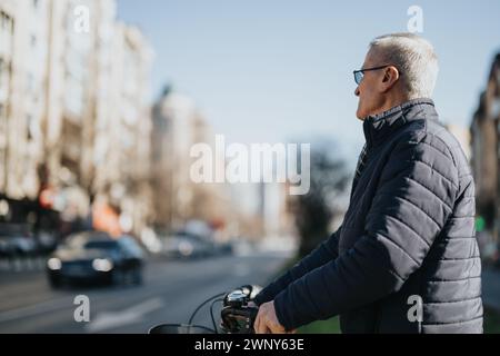 Homme senior profitant d'une promenade tranquille sur son vélo dans la ville. Banque D'Images