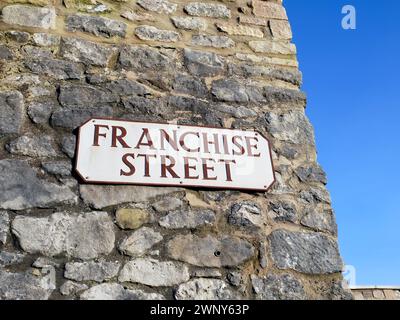 Un panneau de nom de rue pour franchise Street sur un vieux mur de pierre dans la partie de la vieille ville de Weymouth, Dorset, Angleterre avec un ciel bleu clair autour du coin Banque D'Images