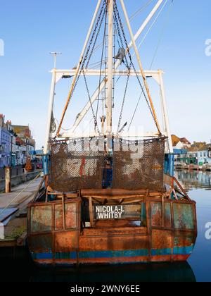 Filets à palourdes ou pétoncles et bateaux de pêche sur la rivière à Weymouth Harbour dans le Dorset, Angleterre avec de vieux bâtiments bordant le port. Banque D'Images