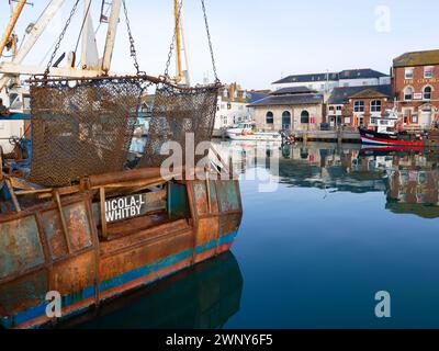 Filets à palourdes ou pétoncles et bateaux de pêche sur la rivière à Weymouth Harbour dans le Dorset, Angleterre avec de vieux bâtiments bordant le port. Banque D'Images