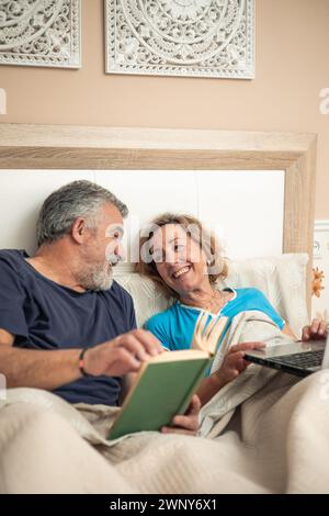 Portrait vertical dans cette scène réconfortante, un couple de personnes âgées partage un moment tendre au lit, leurs yeux se rencontrant avec des sourires conscients et affectueux Banque D'Images