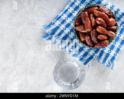 Dattes séchées dans un bol et un verre d'eau sur une serviette en lin, nourriture Ramadan, espace copie, vue de dessus Banque D'Images
