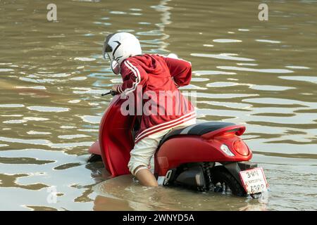 Un homme pousse une moto dans une rue inondée, Thaïlande Banque D'Images