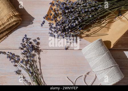 Vue de dessus plat de procédé faisant des bouquets de fleurs de lavande séchées. Corde de coton, ciseaux. Femelle faire bouquet d'herbes maison. Préparation pour l'hiver Banque D'Images