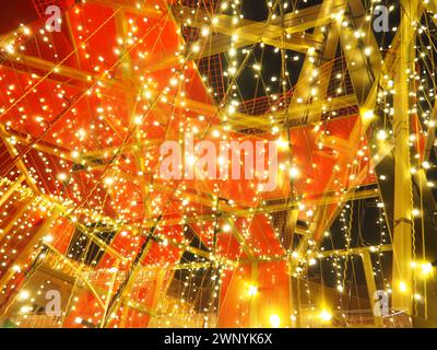 Abstraction et double exposition. Décorations rouges de rue pour le nouvel an et joyeux Noël. Briller de nombreuses ampoules jaunes et blanches dans l'obscurité Banque D'Images