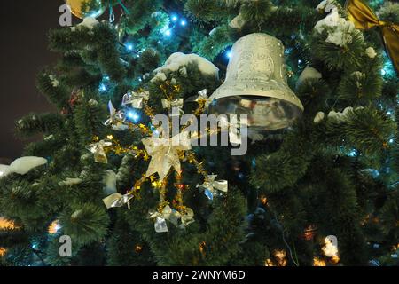 Décorations du nouvel an sur un arbre de Noël de rue. Un flocon de neige, des guirlandes, une cloche et des ampoules oscillent dans le vent. Décor de vacances. Jouets faits maison sur un Banque D'Images