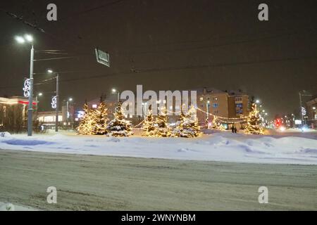 Petrozavodsk, Carélie, Russie, 01.13.2024 : place Gagarine, vue sur l'avenue Lénine, arbres de Noël. Hiver soir ou nuit, neiges près de la route Banque D'Images
