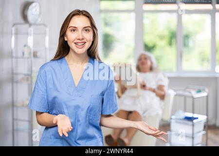 Femme médecin cosmétologue debout avec la femme regardant miroir derrière dans le bureau des médecins. Banque D'Images