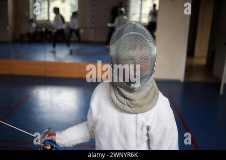 Odessa, Ukraine. 02 mars 2024. Un jeune escrimeur dans un casque de bouclier vu pendant la formation d'escrime dans une école spécialisée de la rue Novoselsky. De jeunes sportifs athlètes d'escrime s'entraînent à l'école, sur la guerre en cours entre la Russie et l'Ukraine. L'entraîneur honoré de l'Ukraine Oleksander Vasutin forme des athlètes. Les athlètes s'entraînent avec des entraîneurs ; Oleksander Vasutin, Mykyta Stolbunov et Volodimir Pokatilov. (Photo de Viacheslav Onyshchenko/SOPA images/SIPA USA) crédit : SIPA USA/Alamy Live News Banque D'Images