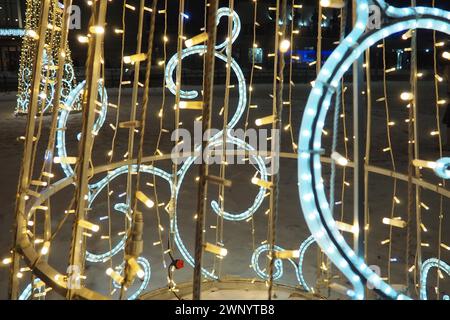 Beaux luminaires électriques de guirlandes de rue. Nouvel an et décoration de Noël des rues de la ville. Blanc scintillant clignotant, jaune et bleu Banque D'Images
