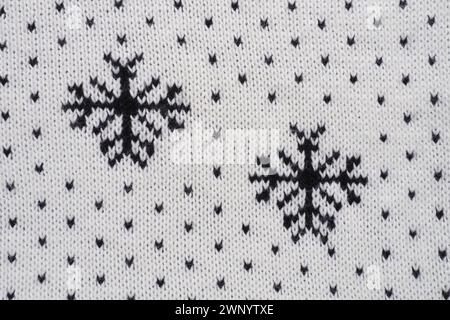 Motif tricoté jacquard. Ornement géométrique pour Noël ou nouvel an. Flocons de neige noirs tricotés et points sur fond blanc. Hiver tendance moderne Banque D'Images
