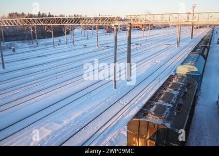 Gare ferroviaire. Trains de marchandises voyageurs sur rails. Hiver court jour polaire. Neige et déneigements Banque D'Images