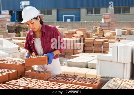 Femme portant des briques d'argile dans le stockage extérieur Banque D'Images