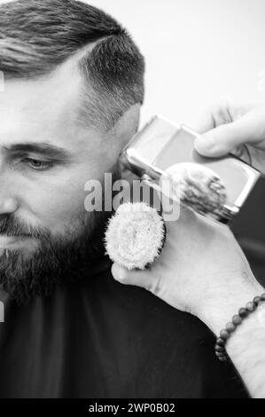 Barber rase la tempe avec une tondeuse sans fil lors d'une courte coupe de cheveux sur les côtés de la tête. Banque D'Images