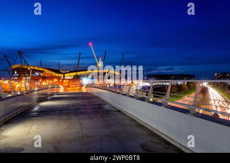 Photo de nuit du stade Etihad à Manchester et de la circulation en dessous de la passerelle Banque D'Images