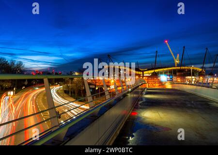 Photo de nuit du stade Etihad à Manchester et de la circulation en dessous de la passerelle Banque D'Images