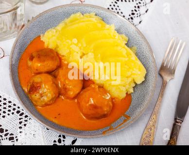 assiette ronde blanche avec boulettes de viande saupoudrées d'aneth haché dans une sauce tomate avec purée de pommes de terre Banque D'Images