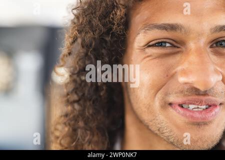 Gros plan d'un jeune homme biracial avec les cheveux bouclés et un sourire chaleureux Banque D'Images