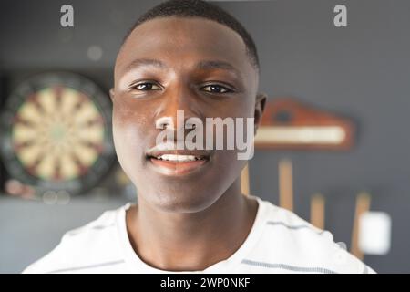 Un jeune homme afro-américain avec une expression agréable se tient à l'intérieur Banque D'Images