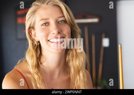 Jeune femme caucasienne aux cheveux blonds et un sourire amical se tient à l'intérieur Banque D'Images