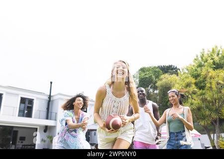 Groupe diversifié d'amis profiter d'un jeu ludique de football en plein air avec espace de copie Banque D'Images