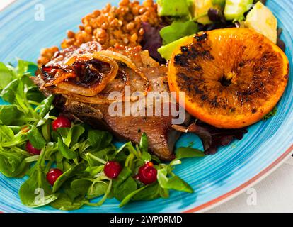 Shin de porc rôti avec lentilles, avocat, vert et orange grillé Banque D'Images