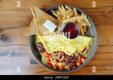 Une assiette de nourriture avec un œuf frit, des toasts et des frites. L'assiette est sur une table en bois Banque D'Images