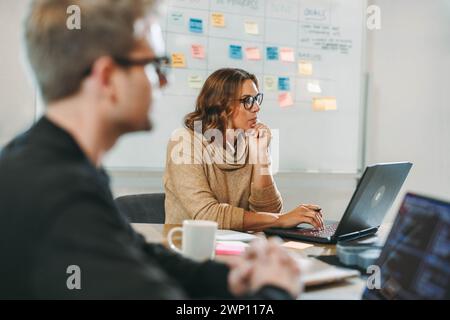 Les professionnels d'une entreprise technologique diversifiée s'engagent dans des discussions collaboratives, travaillant ensemble dans une salle de conseil. Focalisé sur les projets logiciels, ils utili Banque D'Images