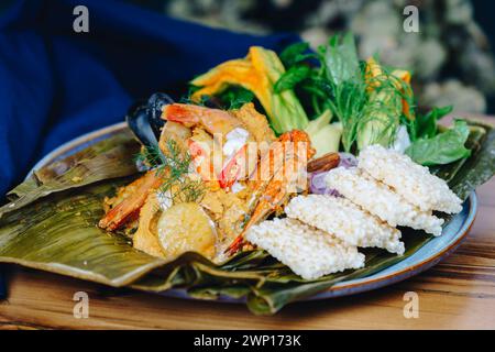 Une assiette de nourriture avec des crevettes, des légumes et du riz. L'assiette est sur une table en bois Banque D'Images