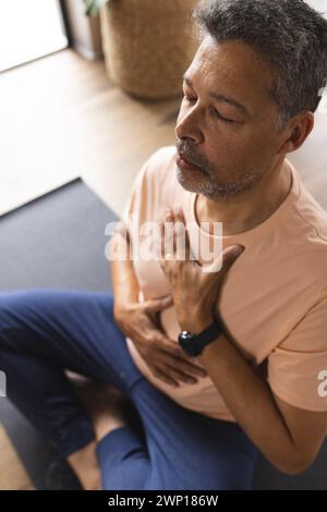 Homme senior biracial médite les yeux fermés, la main sur la poitrine Banque D'Images