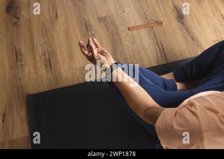 Homme senior biracial médite sur un tapis de yoga, sa main dans un geste mudra Banque D'Images