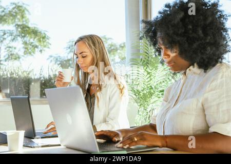Deux femmes d'affaires travaillant sur leurs ordinateurs portables au bureau. Concept commercial. Banque D'Images