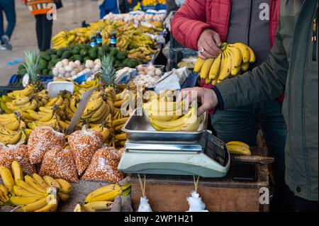 Homme pesant des fruits sur un appareil de pesage dans un marché local. Banque D'Images